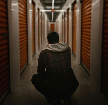 Man crouched looking at business storage units